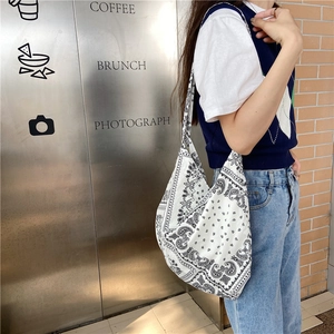 Side view of white and black paisley canvas crossbody bag showing large capacity fit