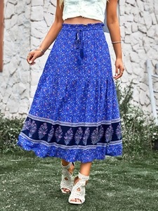 Détail d'une jupe longue bohème bleue à fleurs avec taille élastique et liens à pompons
