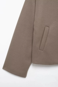Close-up of the thick wool fabric texture and slanted pocket on this brown loose jacket
