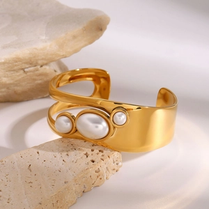 Detailed view of gold plated hollow bangle with white pearls on a natural stone base