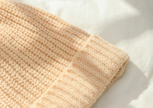 Close-up of cream chunky knit texture and soft wavy stitching on the acrylic beanie