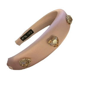 Pink satin padded headband with rhinestone heart jewels on a plain white background