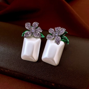 Details von Blumenohrringen mit lila Strass, grünen Blättern und Perlentropfen