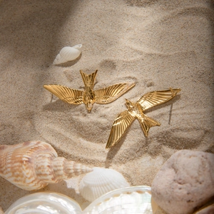 Macro view of 18k gold-plated stainless steel bird earrings with feather texture