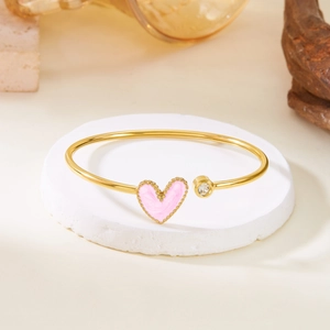 Close-up of pink heart enamel and sparkling zircon on gold stainless steel open bangle