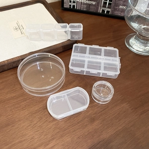 Detail view of transparent plastic jewelry boxes in various shapes on a wooden desk
