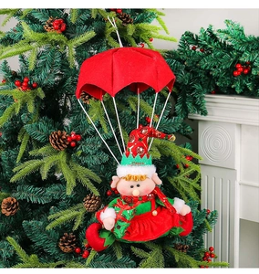 Detail of hanging Christmas parachute elf ornament on a decorated tree with fireplace backdrop