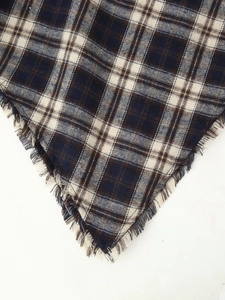 Detail shot of the frayed edges and woven plaid pattern on the hem of the dress