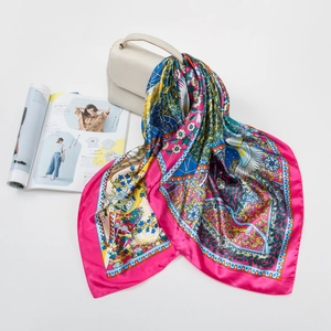 Detail of printed satin silk square scarf tied to a beige handbag on fashion magazine