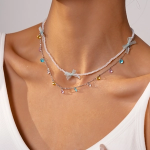 Close-up of a double-layer beaded necklace with mesh bow and colorful crystal charms