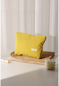 Detail showing yellow corduroy makeup bag with H & R label on a wooden tray