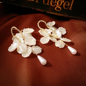 Vintage-Ohrringe mit Muschelpetalen, Kristallen und Perlen auf rotem Seidenhintergrund