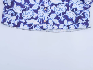 Détail du chemisier à fleurs montrant les boutons en bois et l'ourlet du tissu