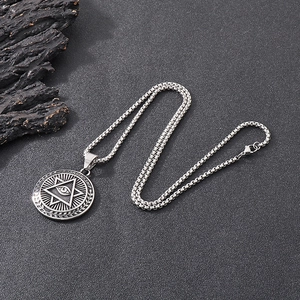 Macro shot of silver metal pendant with Eye of Providence and Guardianship engraving
