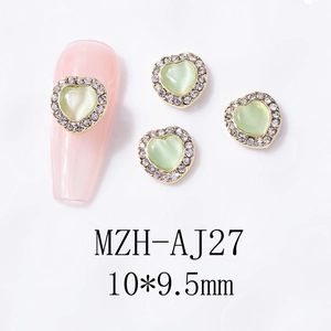 Detailed view of light green cat eye heart nail charm with sparkling rhinestone gold base