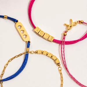 Gros plan de bracelets d'amitié tressés avec perles LOVE et breloques en or 18 carats
