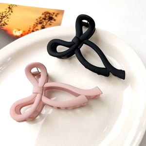 Detail of matte pink and black bow hair claws displayed on a ceramic plate
