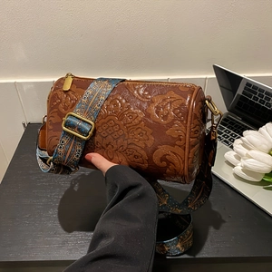 Detail of vintage brown embossed cylinder bag with ethnic style wide woven shoulder strap
