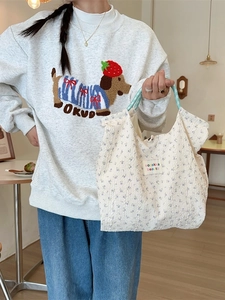 Floral print tote bag with blue checkered handles and embossed texture for daily commute