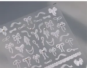 Detailed macro view of 3D embossed white bow nail stickers with pearl and lace textures