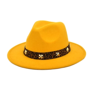 Detailed close-up of the yellow fedora with leopard print band and metal cross studs