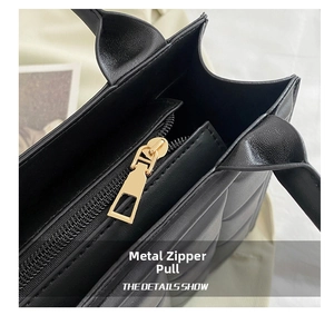 Detailed close-up showing the metallic zipper pull and quilted texture on this black handbag