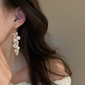 Close-up of model wearing elegant pearl fringe earrings with golden hooks on gray background