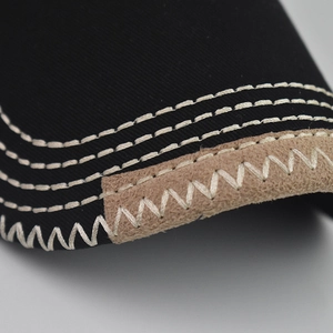 Macro detail of cotton baseball cap brim with multi-row stitching and suede trim