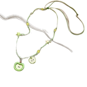 Collier pomme verte fait main avec perles étoiles sur un fond blanc épuré