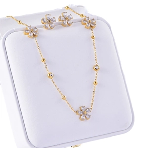 Floral zircon necklace and earrings set in gold finish on a white jewelry box