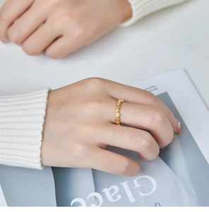 Detailed view of stackable honeycomb pattern gold ring on hand with knit sweater