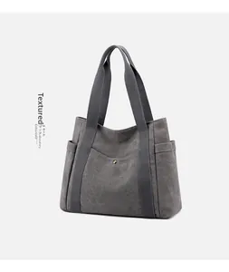 Detail of dark grey canvas tote bag featuring brass buckle pocket and soft fabric texture