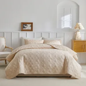 Close-up of beige quilted bedspread set with diamond stitch pattern and matching pillowcases