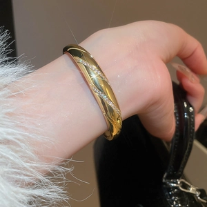 Detail of 18k gold plated bangle with zircon inlay set against white faux fur cuff