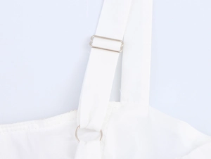 Close-up of white beach dress strap with adjustable metallic buckle and plain fabric
