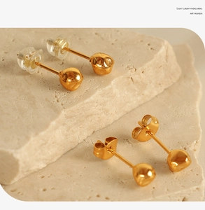 Detail of gold bean stud earrings with metal and silicone backings on stone