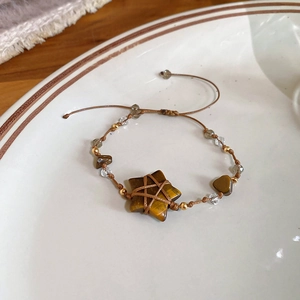 Detail of handmade woven bracelet featuring tiger eye star stone and adjustable brown wax cord