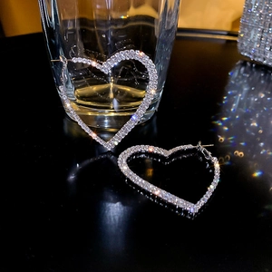 Gros plan de boucles d'oreilles cœur argentées avec strass brillants sur une surface noire