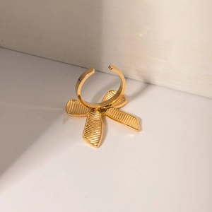 Close-up of golden bow-shaped open ring made of high-quality stainless steel on white surface