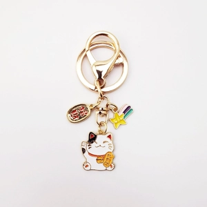 Japanese lucky cat keychain with gold coin and yellow star charm on white background
