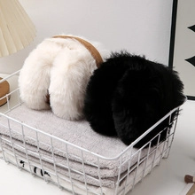 Detail of white and black faux fur plush items in a white wire basket for jewelry storage