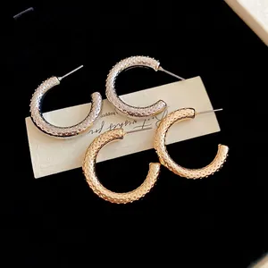 Textured gold and silver C-shaped hoop earrings with vintage hammered dotted finish