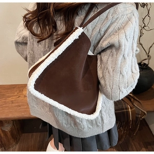Detail of dark brown suede tote bag with white faux shearling trim and slim strap