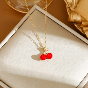 Detail of gold cherry pendant necklace with red beads and crystal leaves on jewelry box