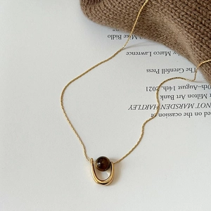 Detail of tiger eye stone pendant on gold chain necklace against cozy knit background