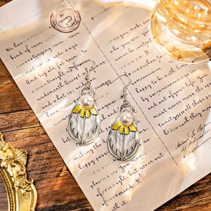 Macro detail of Bohemian teardrop earrings with pearl accents on vintage paper