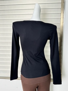 Vista posteriore di un top in maglia nera a maniche lunghe con vestibilità slim