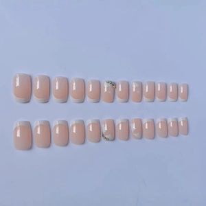 French press-on nails with nude pink base, white tips, and colorful rhinestones