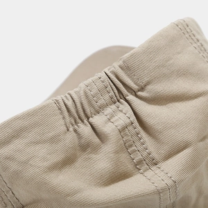 Detail of the elastic back closure and canvas texture on the beige newsboy cap