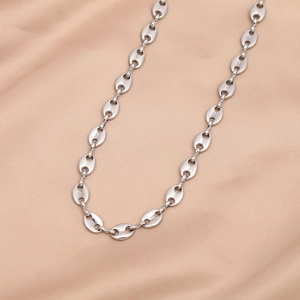 Close-up of polished silver pig nose chain links on elegant champagne silk fabric